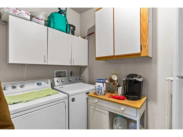 a utility room with stainless steel appliances white cabinets and a refrigerator