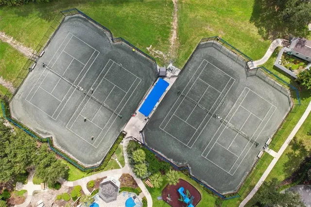 a view of a tennis ground with large trees