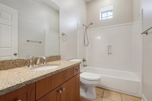 a bathroom with a granite countertop sink a toilet and shower