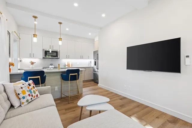a living room with stainless steel appliances kitchen island furniture and a flat screen tv