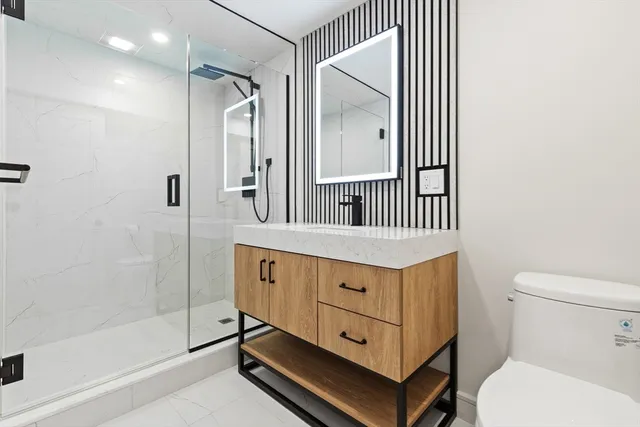 a bathroom with a sink a mirror a toilet and shower