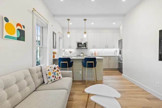 a living room with stainless steel appliances furniture and a kitchen view