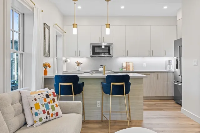 a kitchen with stainless steel appliances kitchen island granite countertop a refrigerator a stove a sink a dining table and chairs with wooden floor