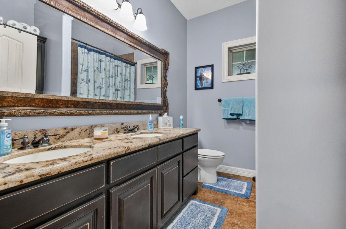 1755 McBride-Devillier Loop Winnie, TX 77665 - Photo 28 of 44 a bathroom with a granite countertop toilet sink and mirror