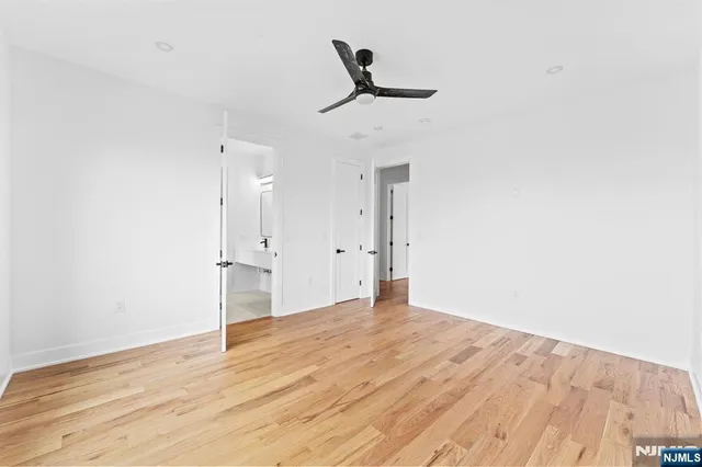 a view of empty room with wooden floor and ceiling fan