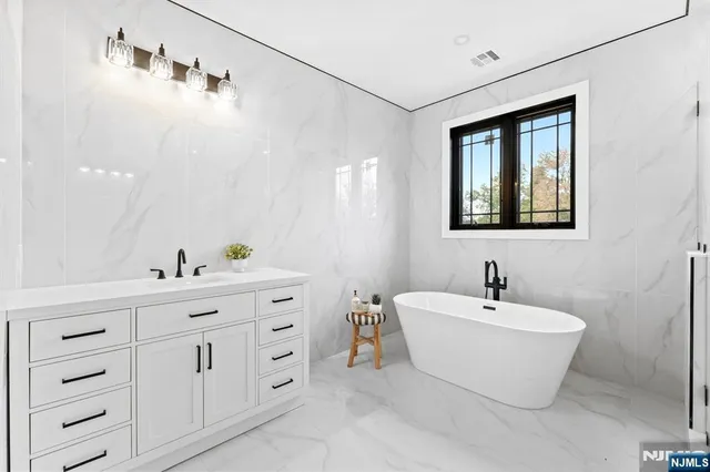 a bathroom with a white tub a sink and mirror