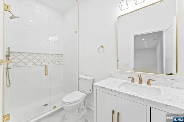 a bathroom with a granite countertop toilet a sink and a mirror
