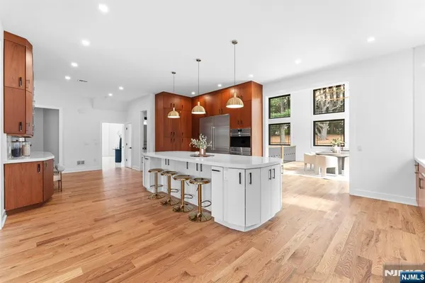 a view of a kitchen with kitchen island stainless steel appliances wooden floor and living room view