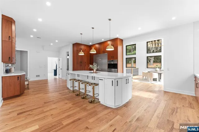 a view of a kitchen with kitchen island stainless steel appliances wooden floor and living room view