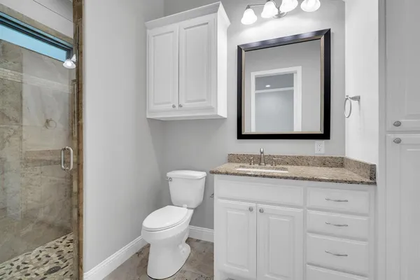 a bathroom with a granite countertop toilet sink and mirror