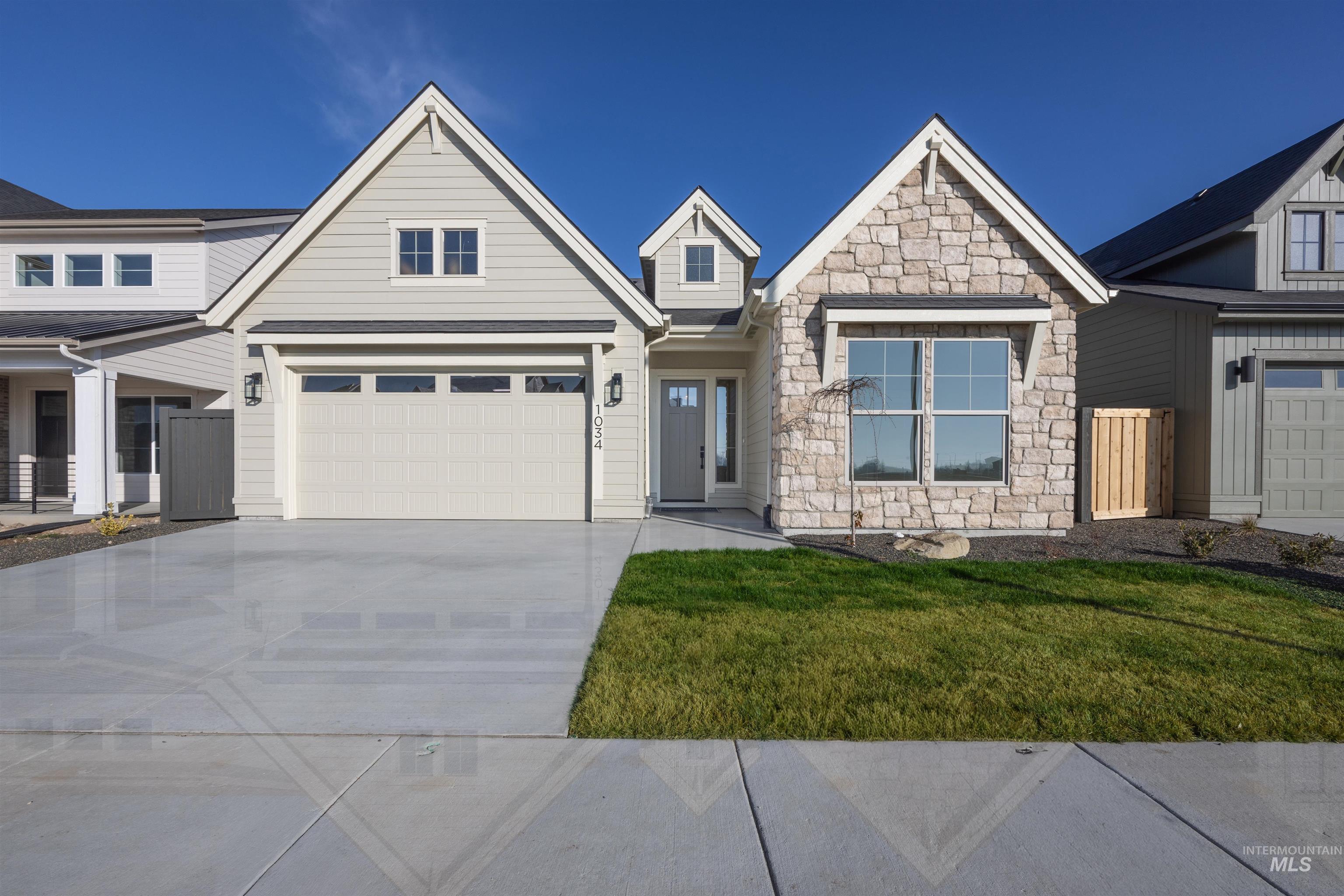 View of front facade featuring stone siding, concrete driveway, a front lawn, and an attached garage
