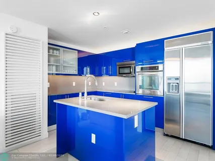 a kitchen with stainless steel appliances granite countertop a table chairs and a refrigerator