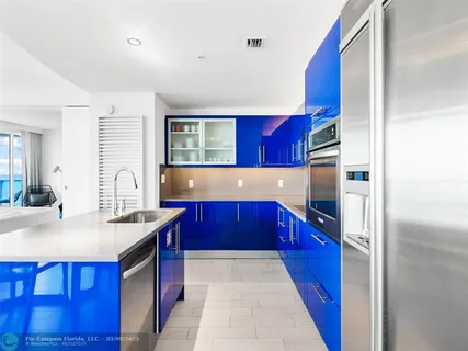 a kitchen with stainless steel appliances granite countertop a red stove top oven a refrigerator and wooden cabinets
