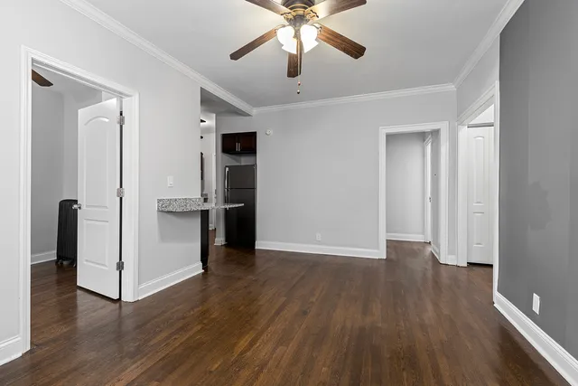 an empty room with wooden floor and a ceiling fan