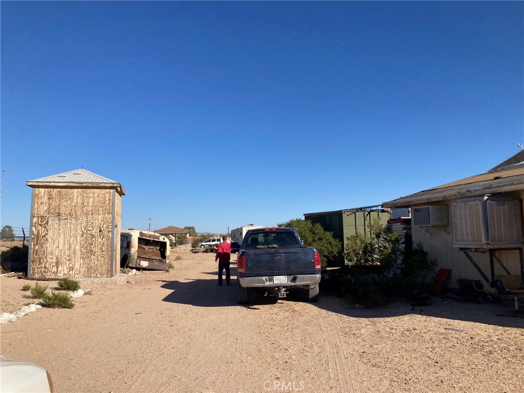 35127 Condor Road Newberry Springs, CA 92365 - Photo 56 of 60 From the driveway area, looking on to the property. The large building is to the right. Straight ahead is the mobile home. To the left is a tall shed with tall tank.