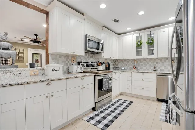 a kitchen with granite countertop white cabinets and white appliances