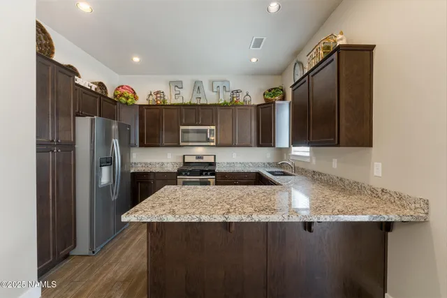 a kitchen with stainless steel appliances granite countertop a refrigerator a sink and a stove