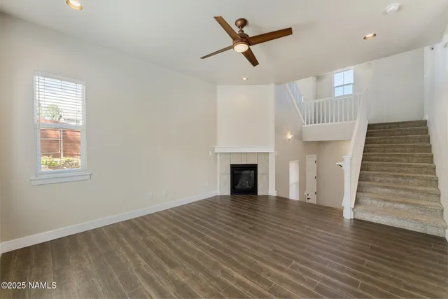 an empty room with wooden floor a ceiling fan and windows