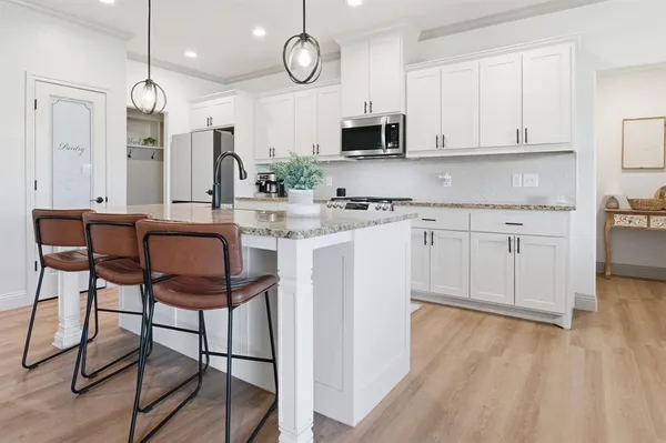 a kitchen with stainless steel appliances granite countertop a stove top oven a sink dishwasher and white cabinets with wooden floor