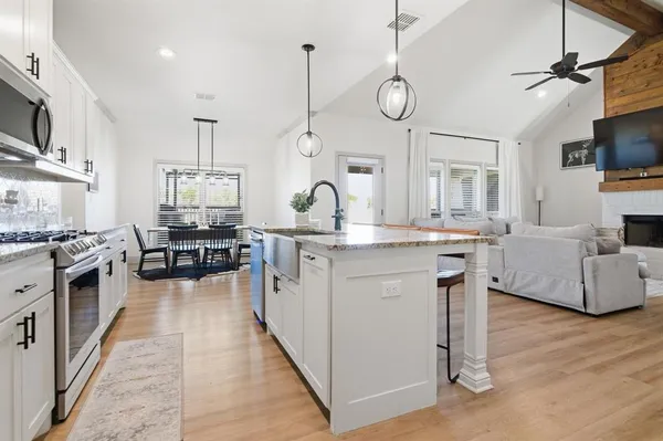 a kitchen with stainless steel appliances granite countertop a sink a stove and chairs with wooden floor
