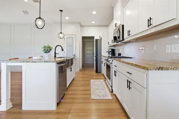 a large kitchen with stainless steel appliances granite countertop a lot of counter space and wooden floors