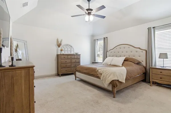 a spacious bedroom with a bed a dresser and mirror