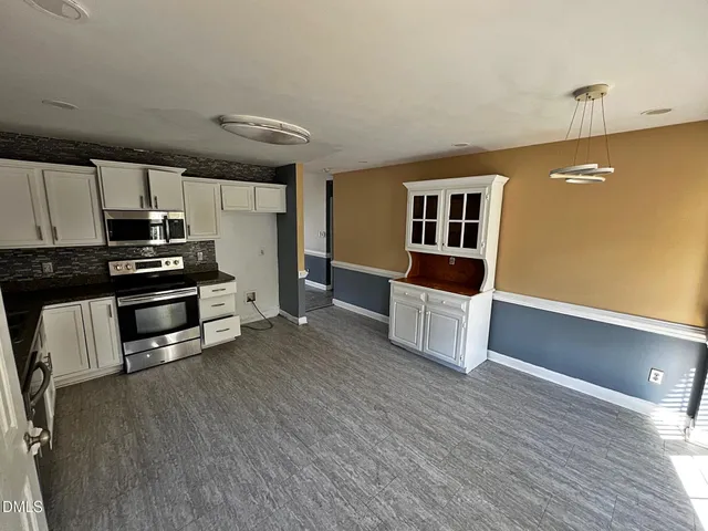 a kitchen with stainless steel appliances kitchen island granite countertop a refrigerator a stove a sink and dishwasher with wooden floor