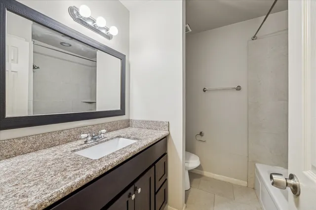 a bathroom with a granite countertop sink a toilet and a mirror