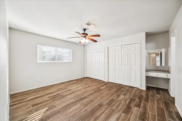 a view of empty room with wooden floor and fan