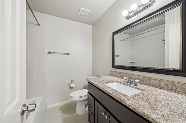 a bathroom with a granite countertop sink a toilet and a mirror