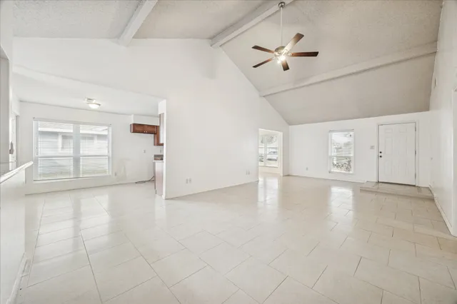 an empty room with ceiling fan and windows