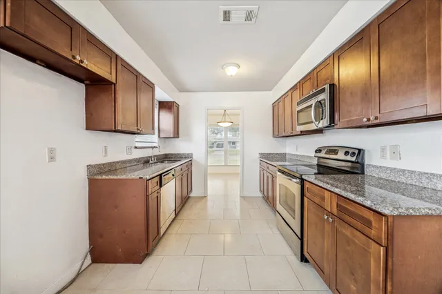 a large kitchen with stainless steel appliances granite countertop a stove a sink and a microwave