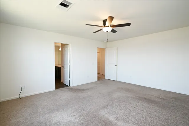 an empty room with closet and a ceiling fan