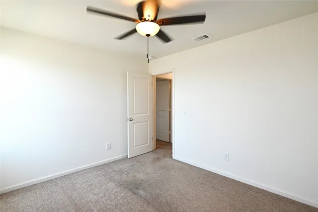 an empty room with a ceiling fan and a fan
