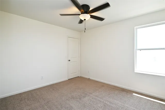 an empty room with a window and a fan