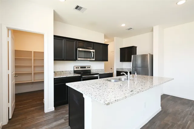 a kitchen with kitchen island granite countertop a sink a counter top space appliances and cabinets