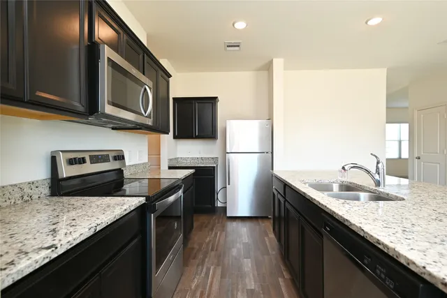 a kitchen with stainless steel appliances granite countertop a sink stove microwave and refrigerator