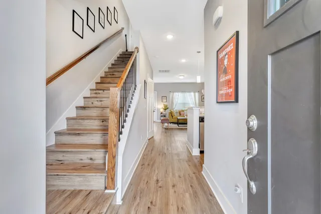 a view of a hallway to a livingroom with wooden floor and stairs