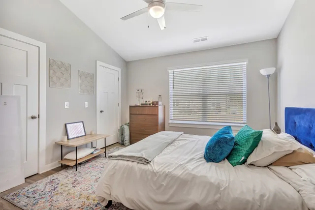 a bedroom with a bed a chair and a large window