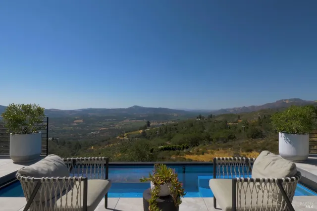 an aerial view of residential house with parking and trees