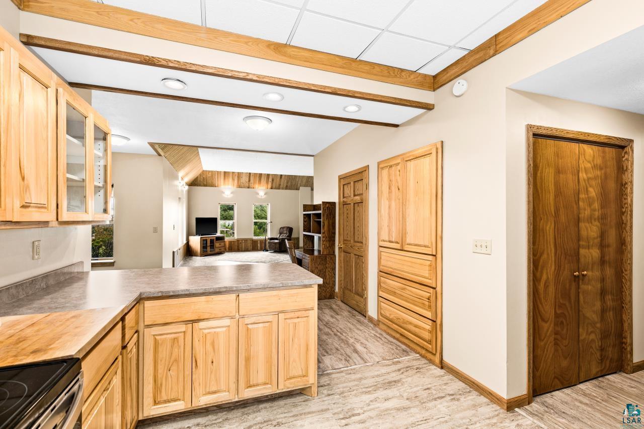 4800 Tower Road Moose Lake, MN 55767 - Photo 13 of 83 Kitchen featuring light wood cabinetry with glass-front accents, solid surface countertops, and wood-finish flooring