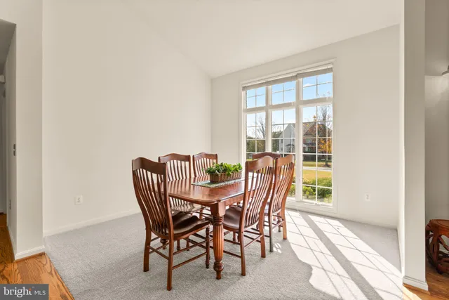 a kitchen with stainless steel appliances granite countertop a refrigerator a sink a stove a dining table and chairs with wooden floor