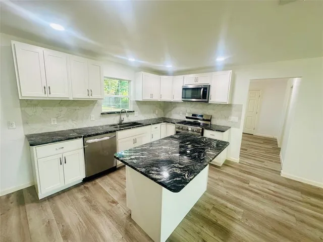 a kitchen with stainless steel appliances granite countertop a stove a sink and a microwave