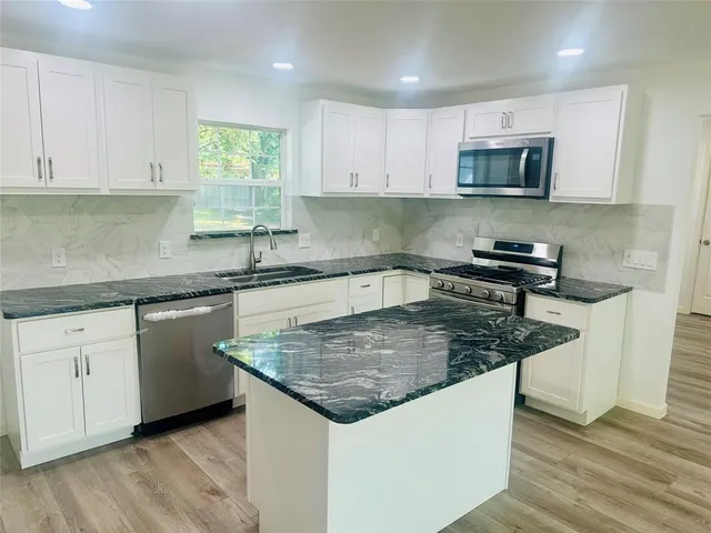 a kitchen with stainless steel appliances granite countertop a sink stove and microwave
