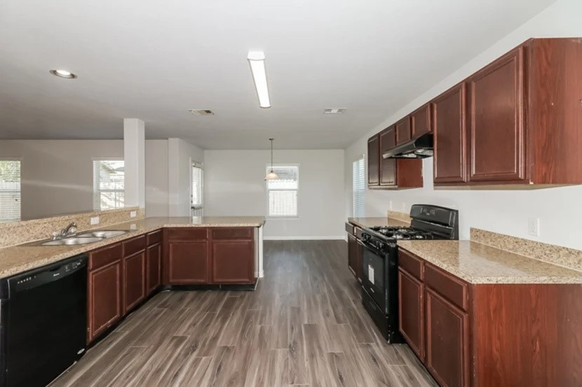 a kitchen with stainless steel appliances granite countertop wooden cabinets a stove top oven a sink and dishwasher