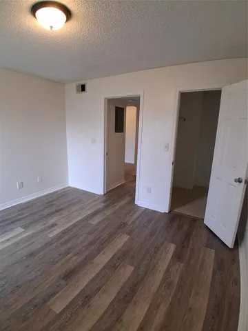 a view of an empty room with wooden floor and closet
