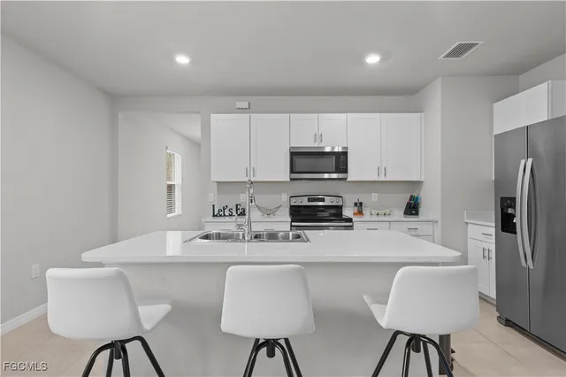 a kitchen with stainless steel appliances granite countertop a dining table chairs refrigerator and sink