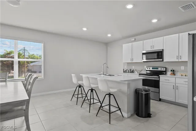 a kitchen with stainless steel appliances granite countertop a stove a sink a microwave a dining table and chairs