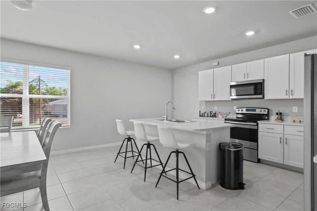 4320 Little Hickory Road Bonita Springs, FL 34134 - Photo 10 of 27 a kitchen with stainless steel appliances granite countertop a stove a sink a microwave a dining table and chairs