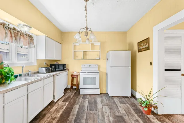 a kitchen with a refrigerator a stove a sink and white cabinets